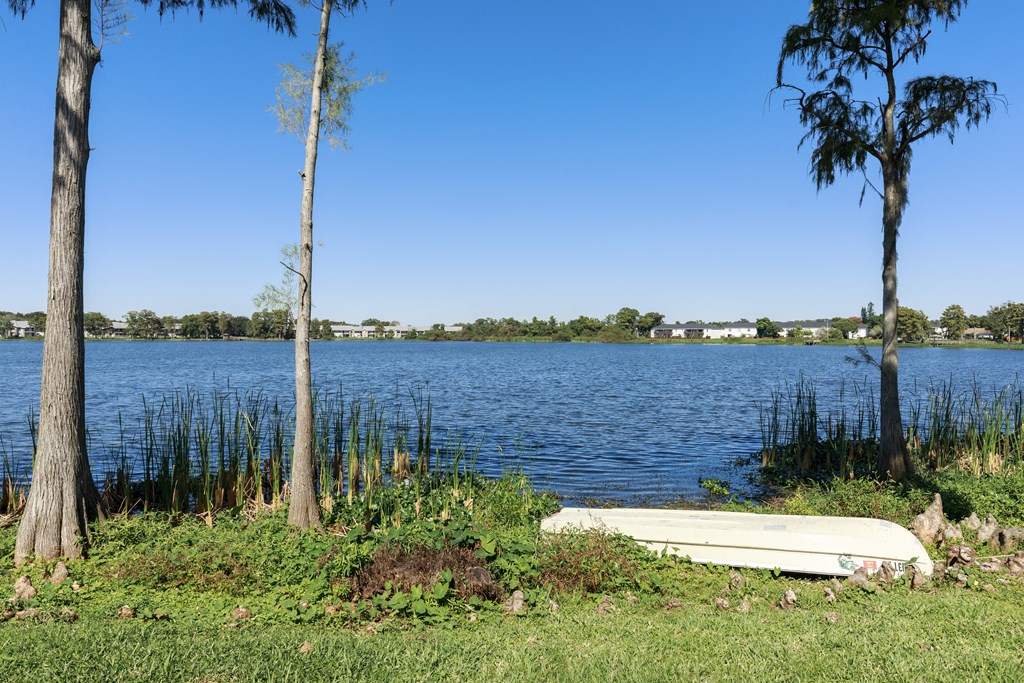 a boat sitting in the grass next to a body of water