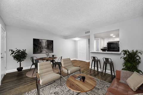 A living room with a brown leather couch, a wooden coffee table, and a painting on the wall.
