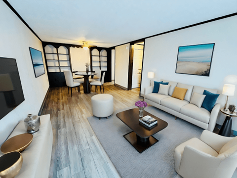 A modern living room with a long white sofa, a coffee table, and a television.