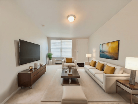 A modern living room with a white sofa, a wooden coffee table, and a large painting on the wall.
