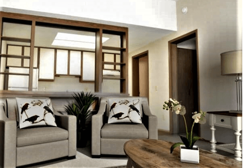 Two grey couches with pillows and a wooden coffee table with a vase of flowers on it.