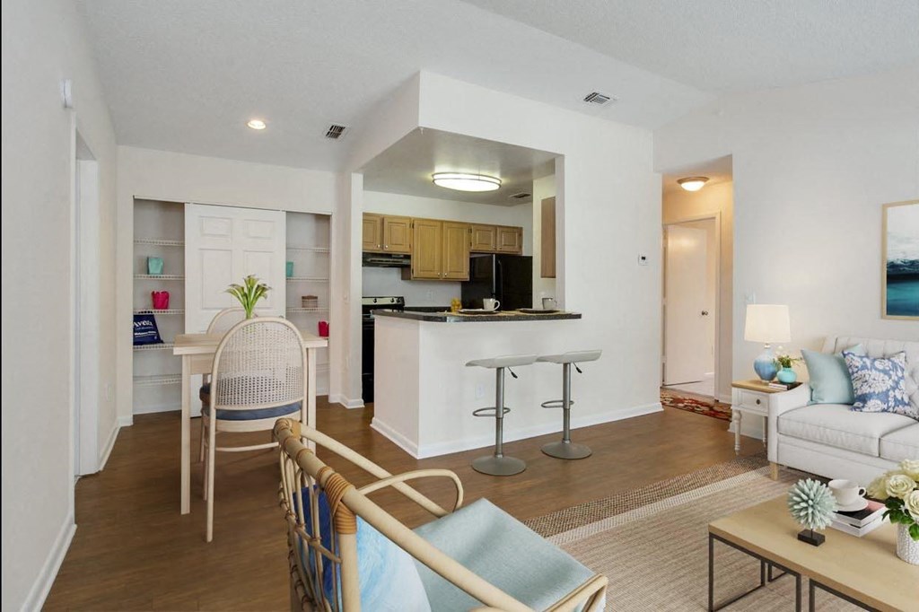 A living room with a kitchen in the background at Aqua Bay Apartments in Naples, FL 34116