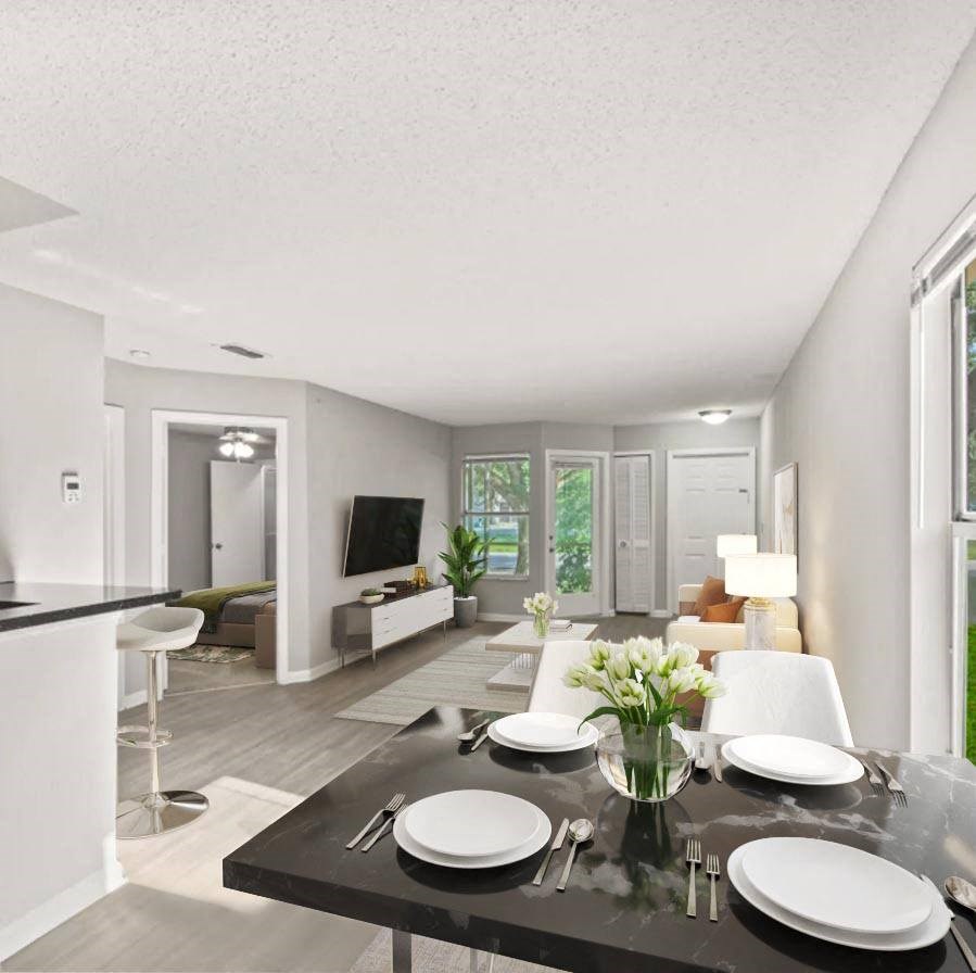 A dining room table with plates and a vase of flowers on top of it at Aqua Bay Apartments in Naples, FL 34116