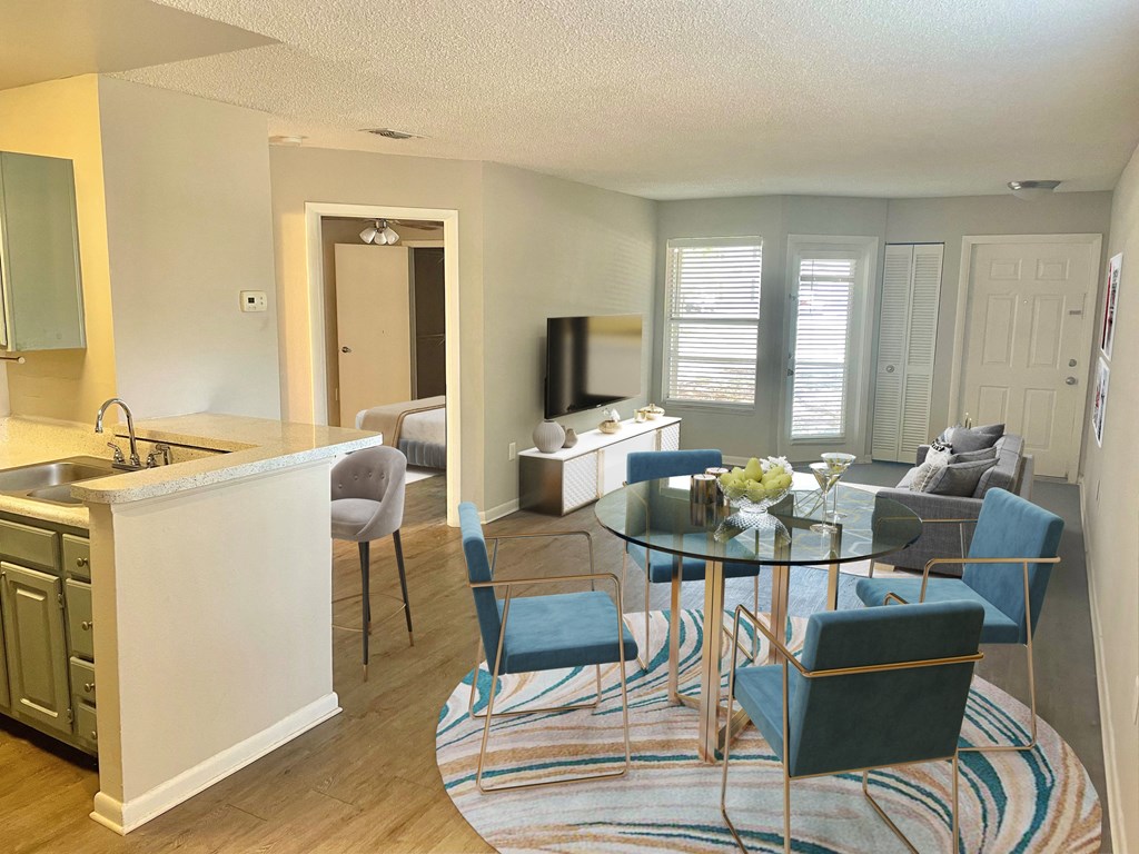 a living room and kitchen with a glass table and chairs at Aqua Bay Apartments in Naples, FL 34116