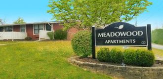 a sign for the meadowwood apartments in front of a brick building