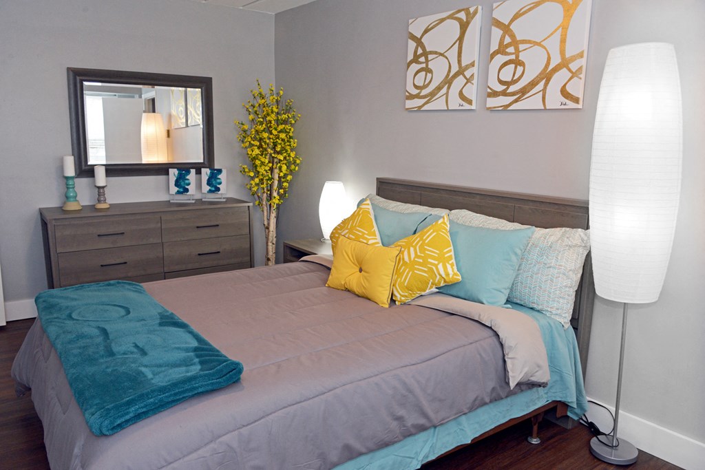 a bedroom with a bed with blue and yellow pillows