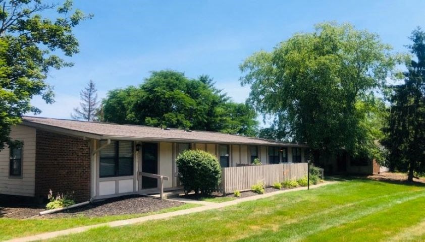 a white and brick house with a yard and a wooden fence