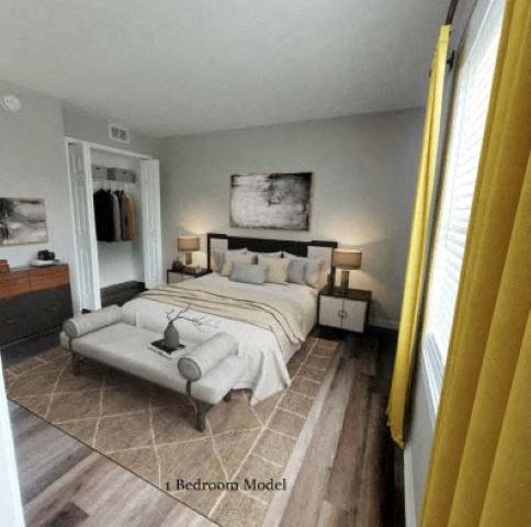 Hardwood-style flooring bedroom with a bed in between two nightstands, a closet, and a window.  