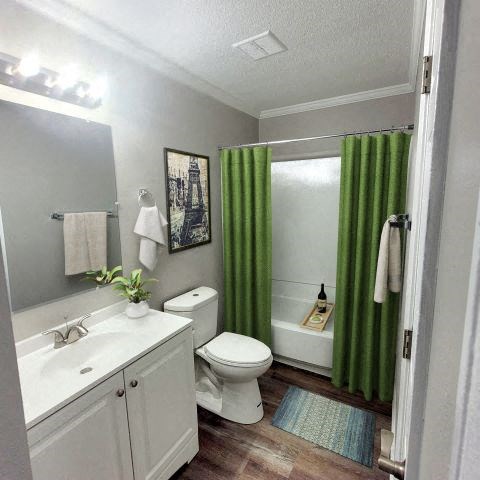 Bathroom with a mirror, vanity lights, a bathtub, a toilet, and a sink with white countertops. 