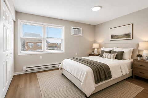 A bedroom with a large bed and a window overlooking a residential area.