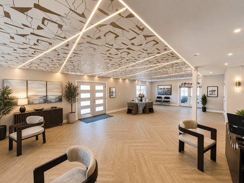 A modern living room with a wooden floor and a ceiling with a unique design.