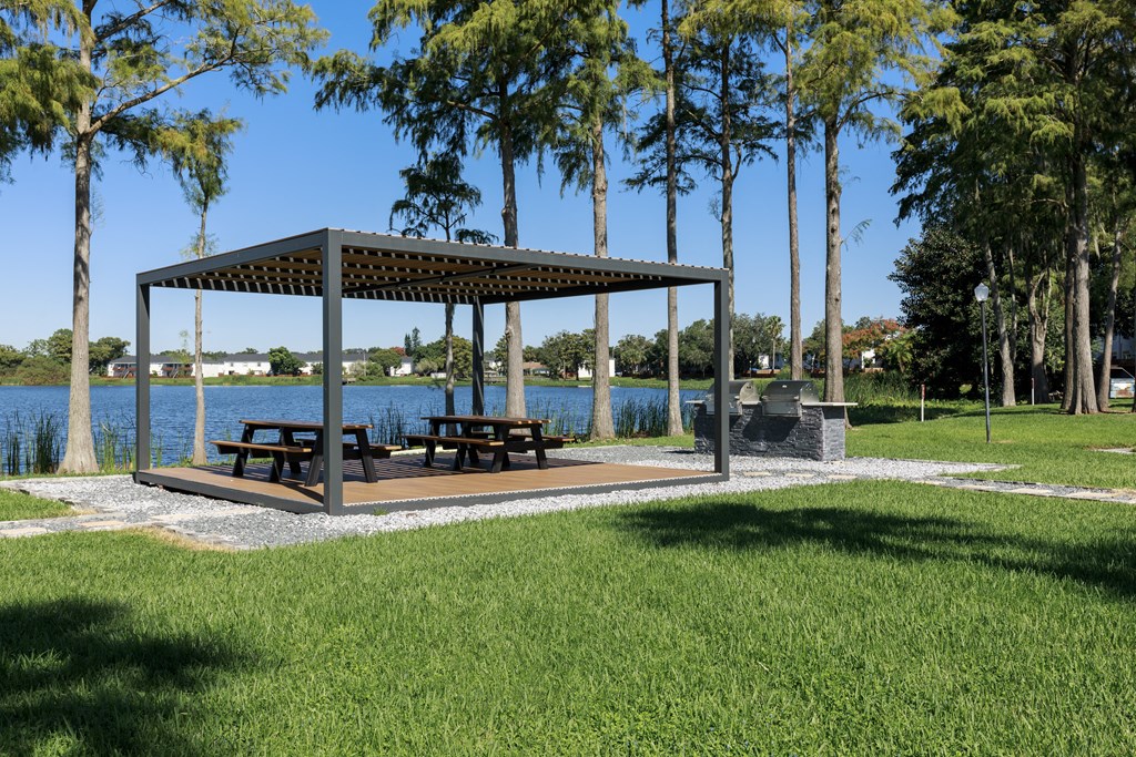 a pavilion with benches in a park next to a lake