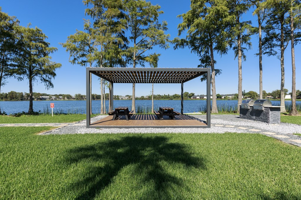 a picnic pavilion in a park next to a lake