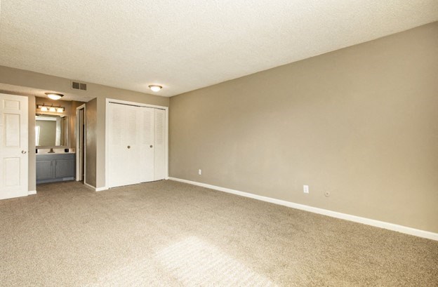 an empty living room with a door to a bathroom
