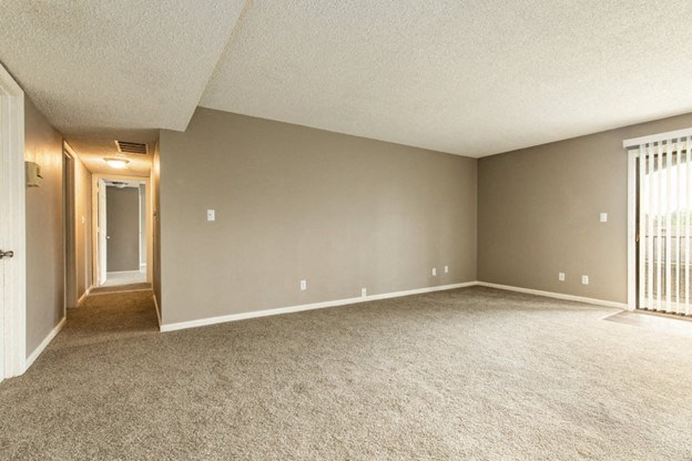 an empty living room with a door to a hallway