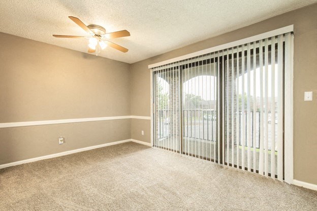 an empty living room with sliding glass doors and a ceiling fan