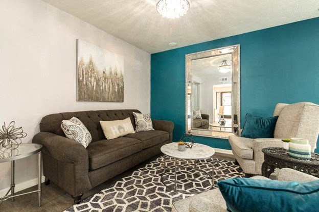 a living room with a couch and a chair and a mirror