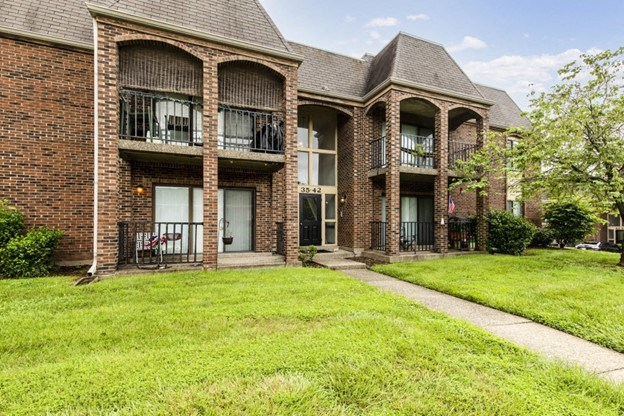 the front of a brick house with grass and a sidewalk