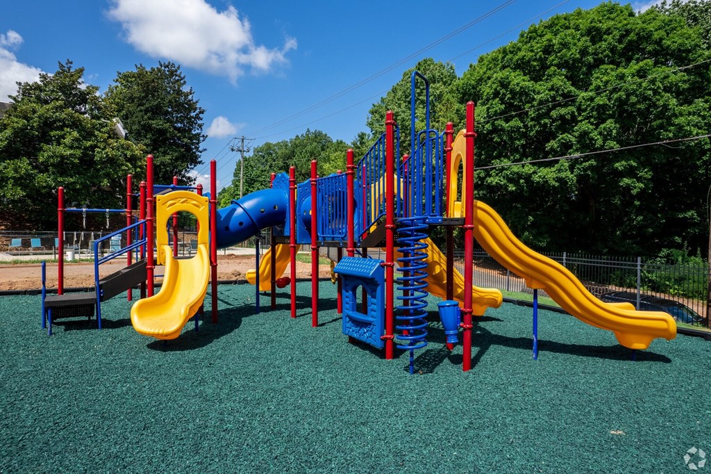 A playground with a blue and yellow slide and a red and blue climbing frame.