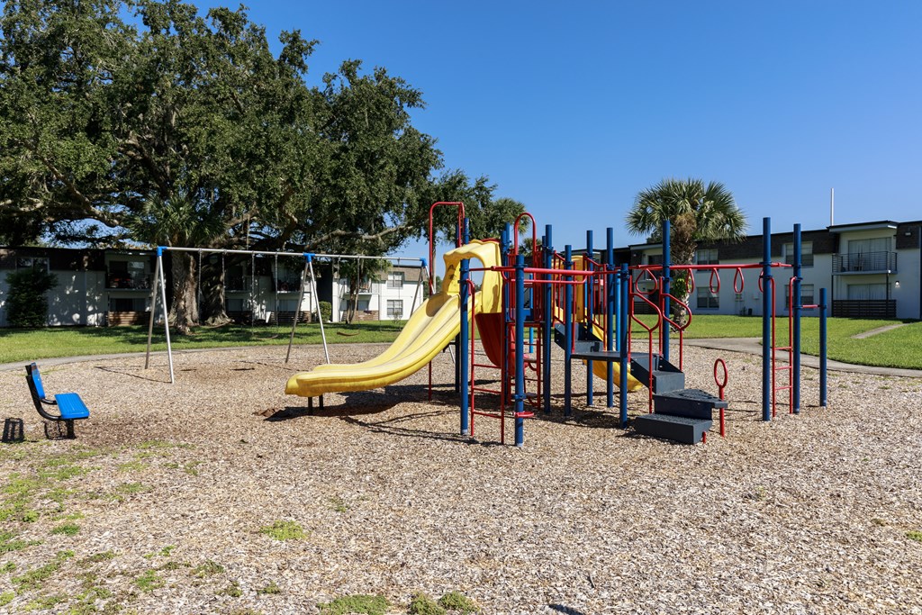 a playground with a yellow slide in a park