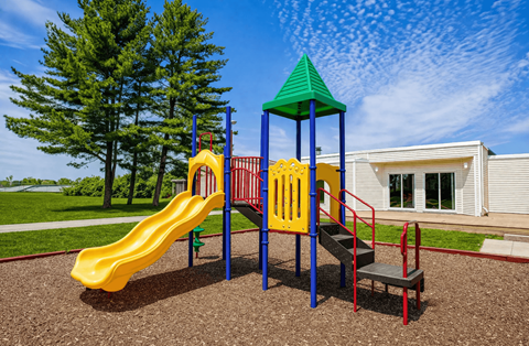 A playground with a yellow slide, a green roofed structure, and a red ladder.