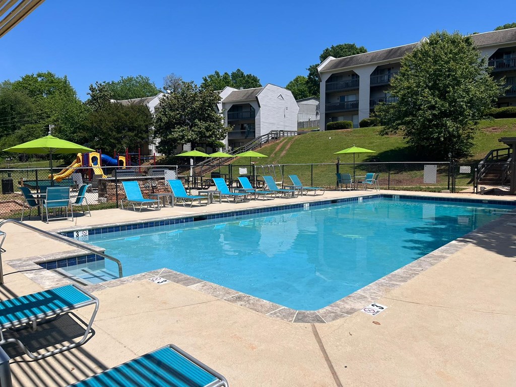 A large swimming pool with a slide and sun loungers.