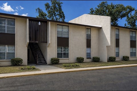 A building with a brown and beige exterior and a black staircase leading to the entrance.