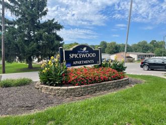 a sign for the spiderwood apartments in a flower garden