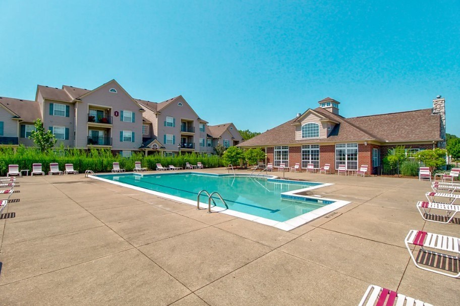 A large swimming pool in front of a building with a red and white striped pool ladder.