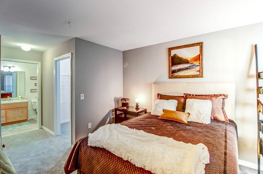 A bedroom with a large bed and a painting on the wall.