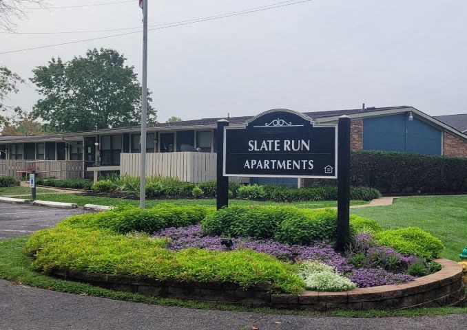 a sign sitting in the middle of a flower garden