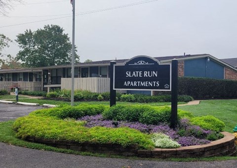 a sign sitting in the middle of a flower garden