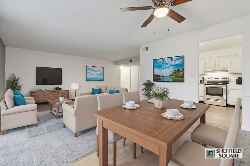 A living room with a wooden table and chairs, a television, and a painting on the wall.