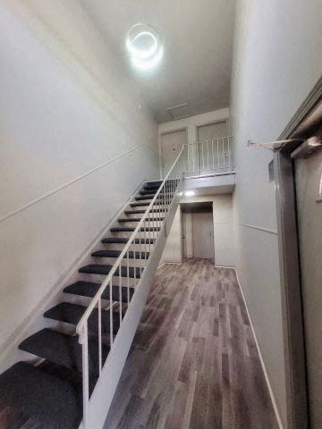 Interior of Woodhaven Park apartment building with hardwood-style flooring and black stairs leading to the second level.  