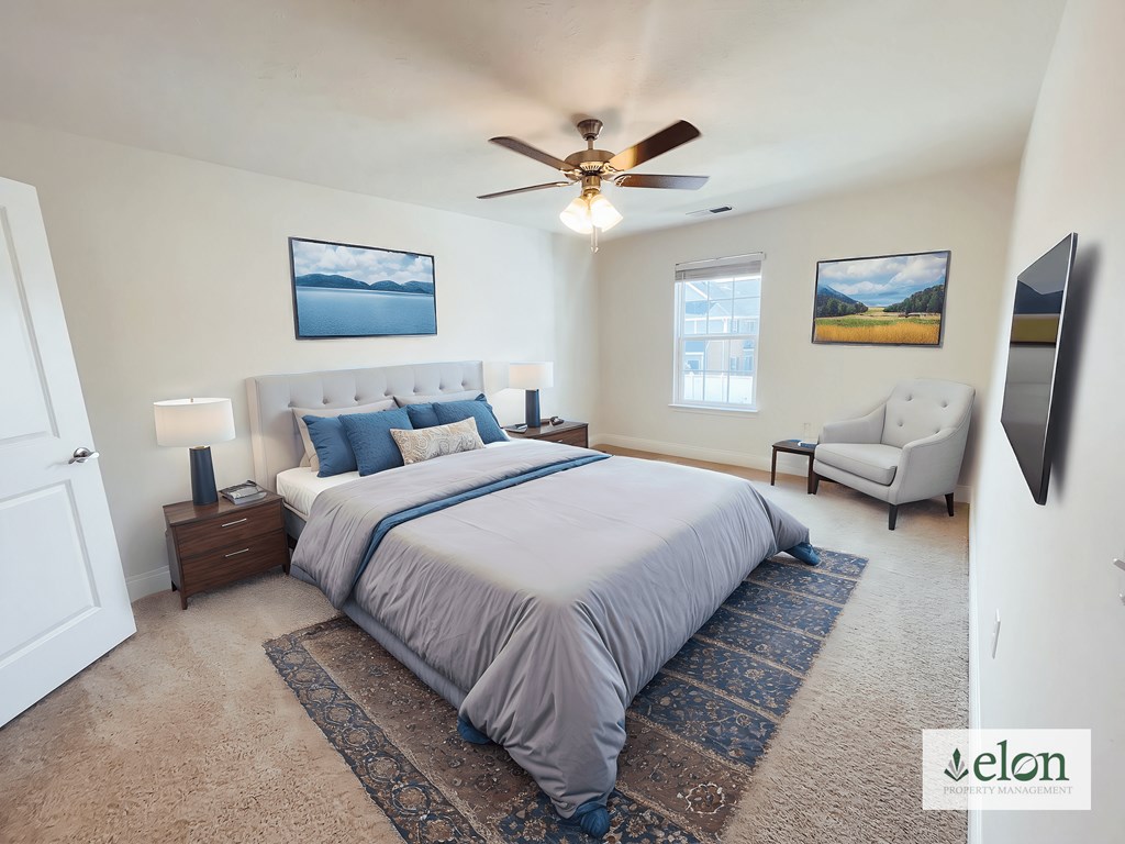 A bedroom with a large bed and a ceiling fan.