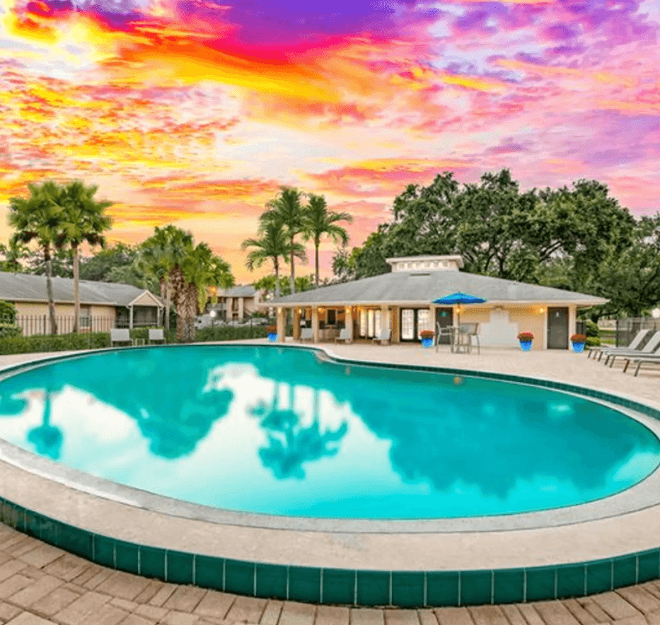 A large swimming pool with a colorful sky in the background at Aqua Bay Apartments in Naples, FL 34116