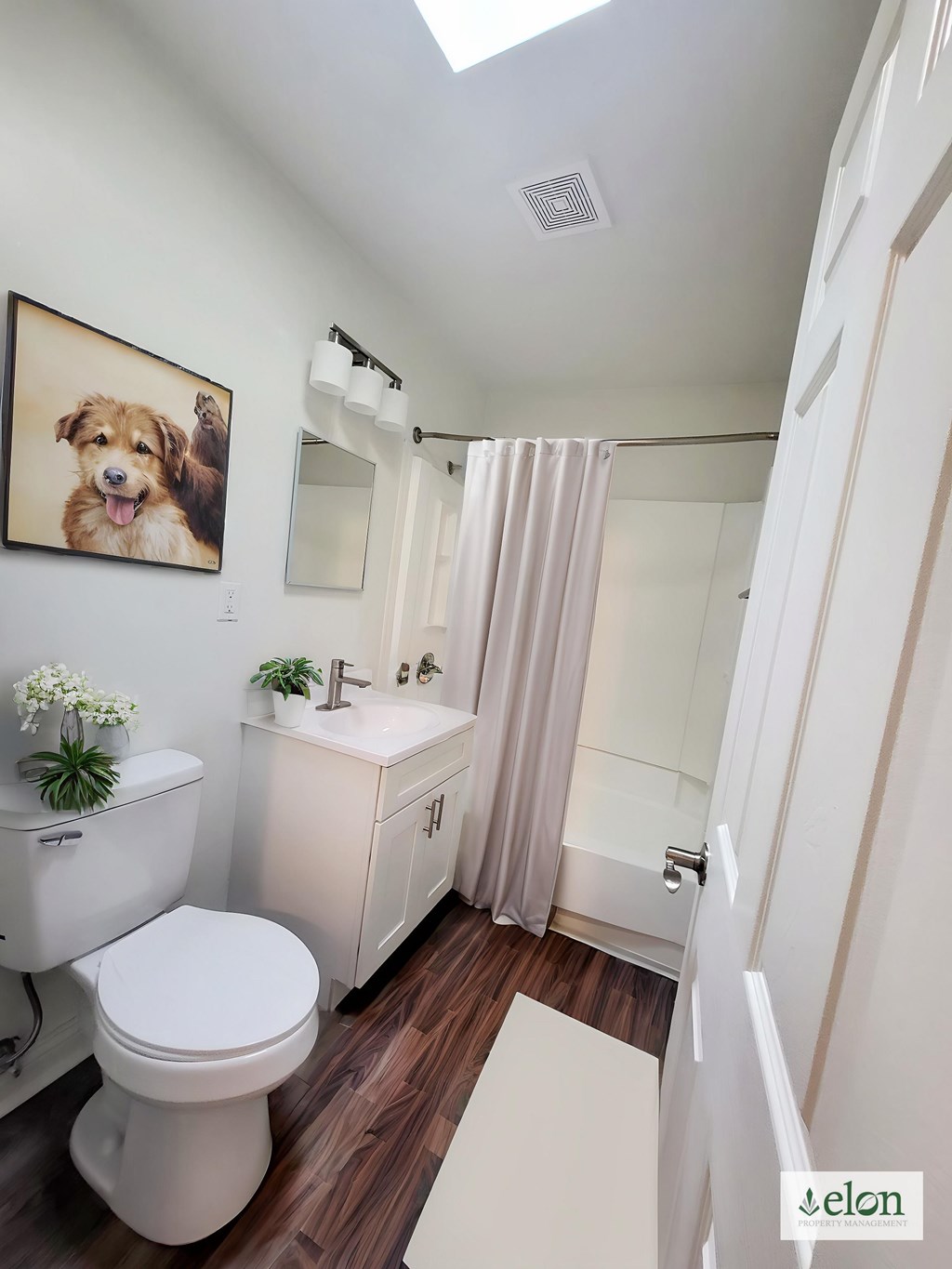 A bathroom with a toilet, sink, and a framed picture of a dog on the wall at Townhomes at 28th, Columbus, Indiana