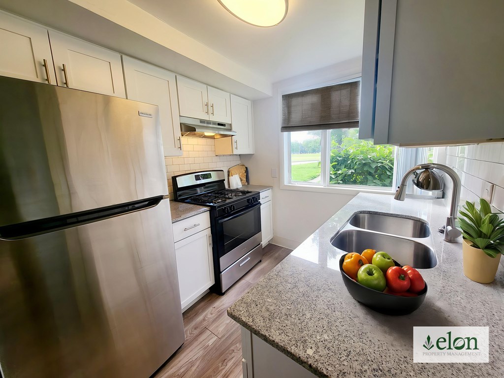 A modern kitchen with a stainless steel refrigerator and a bowl of fruit on the counter at Townhomes at 28th, Columbus, Indiana