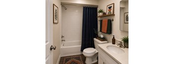 A bathroom with a white toilet, a white sink, a white bathtub, a white rug, a white towel, a white door, a white wall, a white mirror, a white shelf, a white plant,