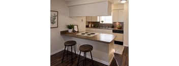 A kitchen with a white countertop and brown stools.