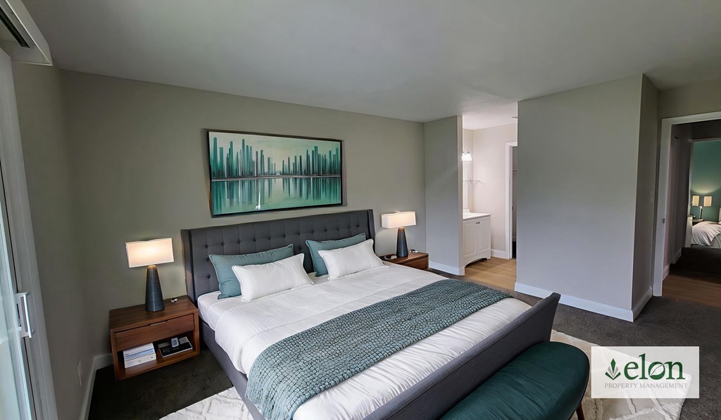 A bedroom with a large bed and a painting on the wall.