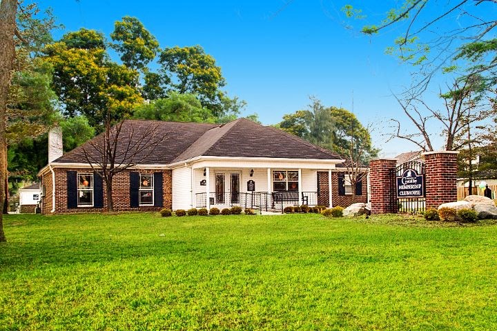 Exterior of the resident clubhouse with a large grassy area and several trees. 