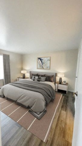 Hardwood-style flooring bedroom with a bed in between two nightstands, white walls, and a window.