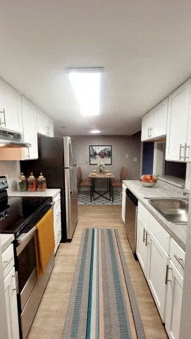 a large kitchen with white cabinets and a rug