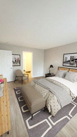 Bedroom with a bed in the middle, a nightstand, a dresser, and 2 photos on the wall.