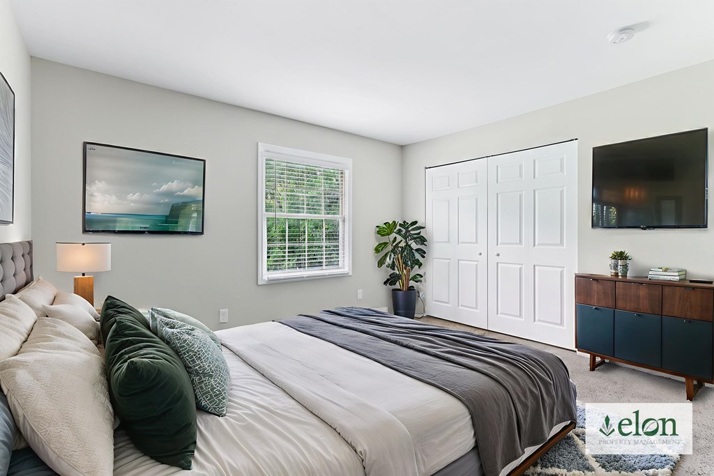A bedroom with a large bed and a painting on the wall.