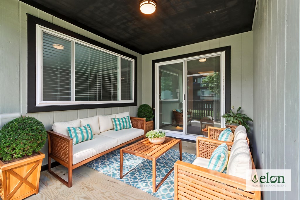A patio with a couch, chairs, and a table with a bowl of fruit on it.