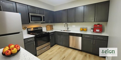 A kitchen with black cabinets and stainless steel appliances.