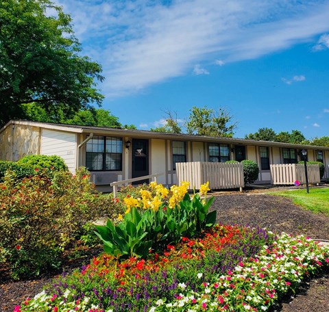 A building with a white picket fence and a flower bed in front.