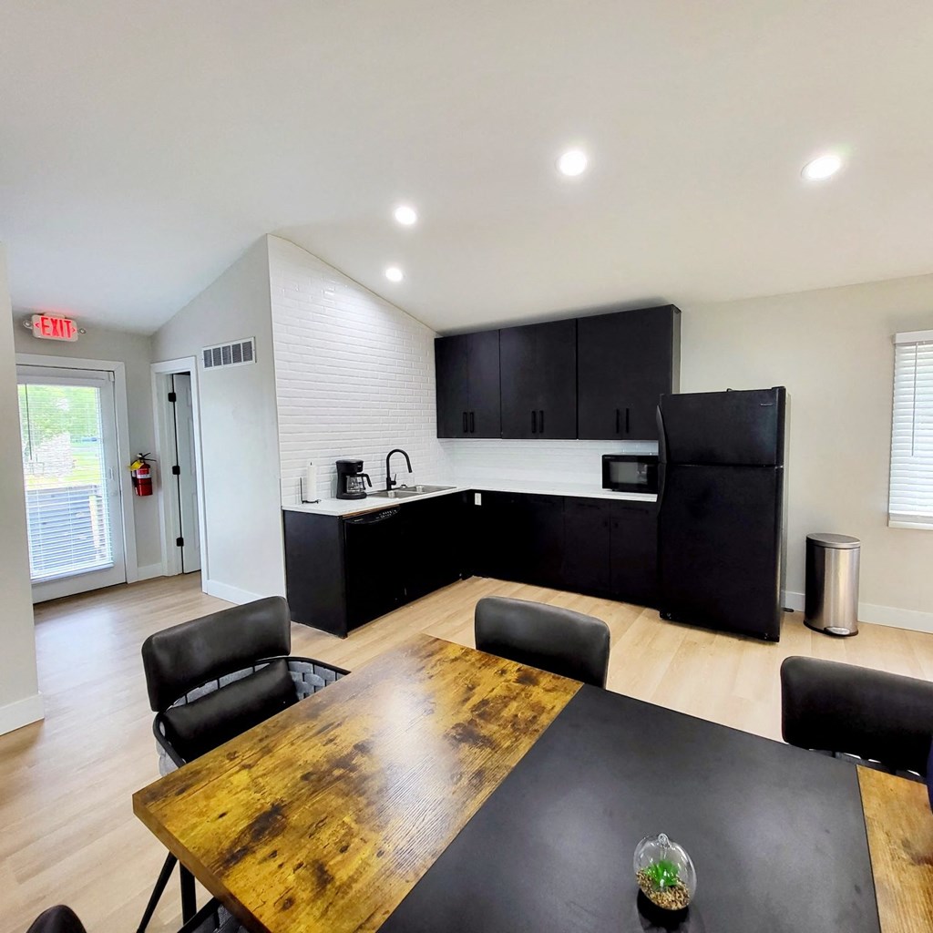 a kitchen and dining room with black cabinets and a wooden table